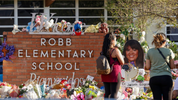 People visit a memorial outside of Robb Elementary