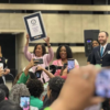 Alpha Kappa Alpha Sorority, Incorporated International President Danette Anthony Reed hoists certificate after organization breaks world record for most personal hygeiene kits assembled in one hou