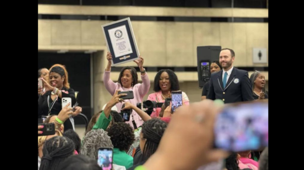 Alpha Kappa Alpha Sorority, Incorporated International President Danette Anthony Reed hoists certificate after organization breaks world record for most personal hygeiene kits assembled in one hou