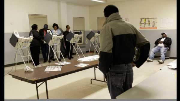 While two voters wait patiently at right